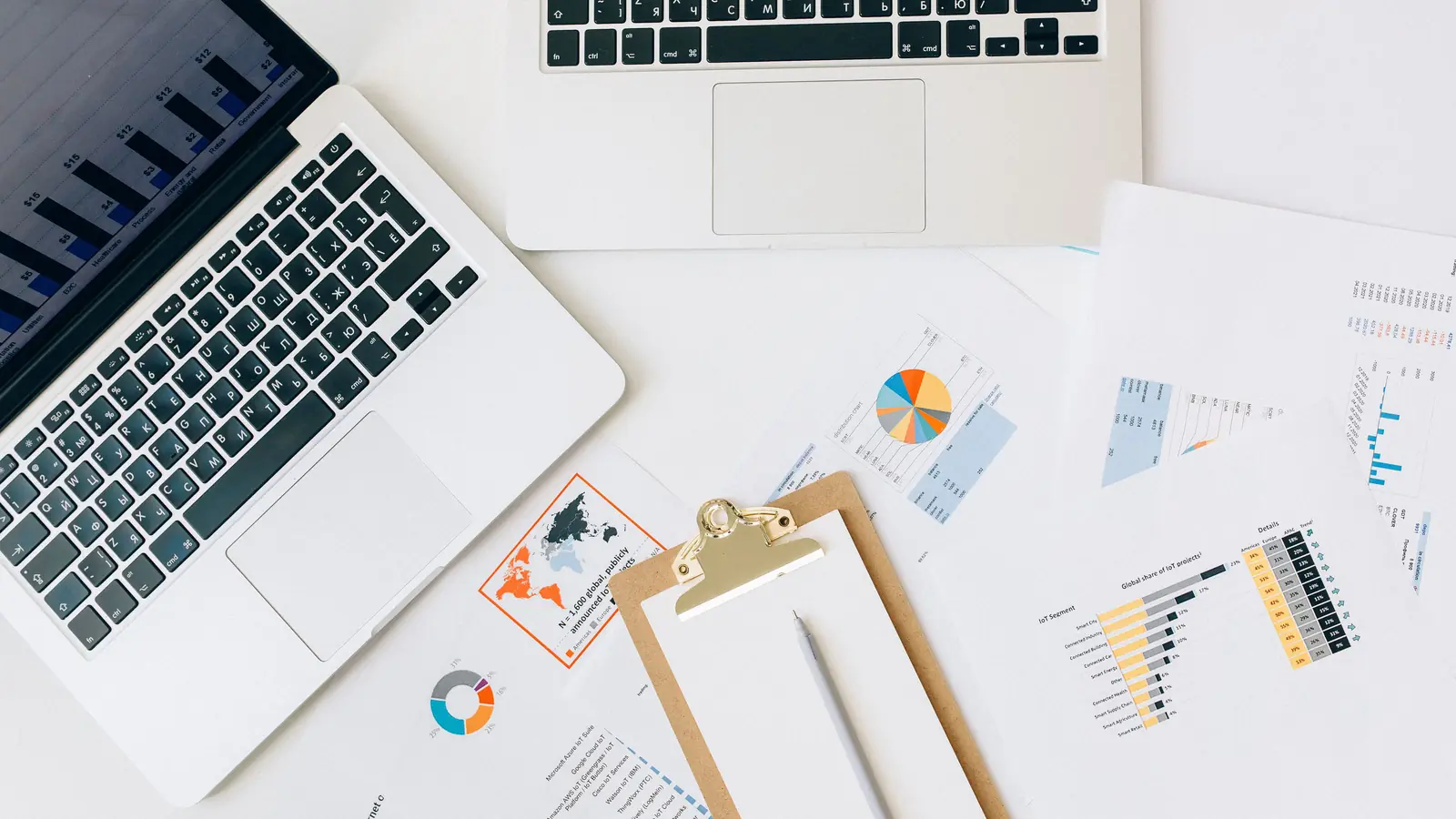 Documents d'analyse et graphiques étalés sur un bureau, avec un ordinateur portable affichant des données